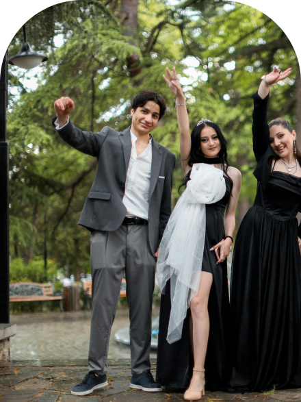 A joyful group of friends celebrating outdoors, dressed elegantly in tuxedos and gowns.